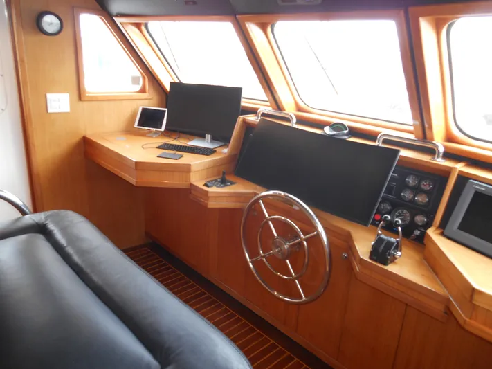 Suspense Yacht Photos Pics 2005 Inace Trawler helm with wooden interior, steering wheel, and navigation equipment.