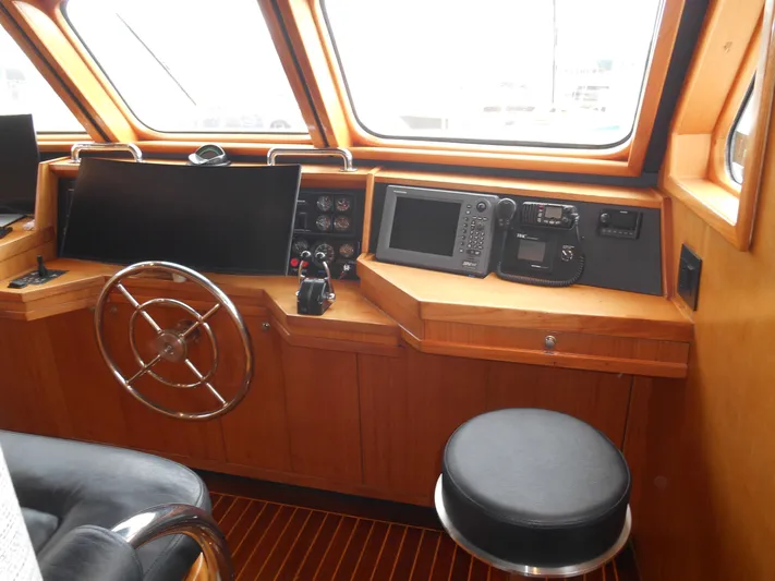 Suspense Yacht Photos Pics 2005 Inace Trawler helm with steering wheel, navigation equipment, and wooden interior.