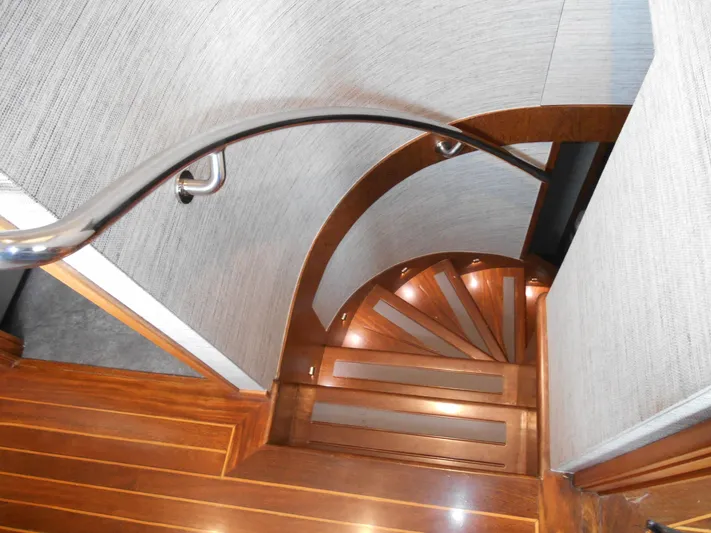 Suspense Yacht Photos Pics Wooden spiral staircase inside 2005 Inace Trawler yacht, featuring sleek handrail and modern design.