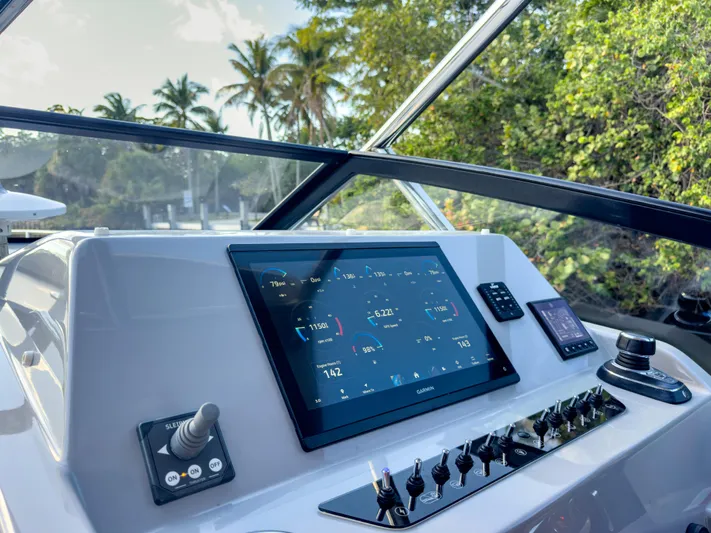  Yacht Photos Pics 2024 Beneteau Flyer 10 dashboard with advanced navigation system, surrounded by lush greenery.