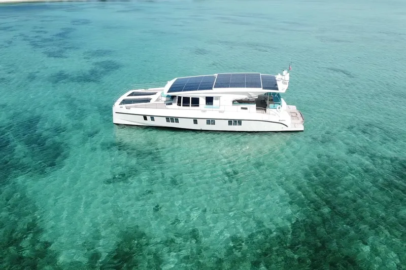 Firefly Yacht Photos Pics Aerial view of 2018 Serenity 64 yacht with solar panels on turquoise water.