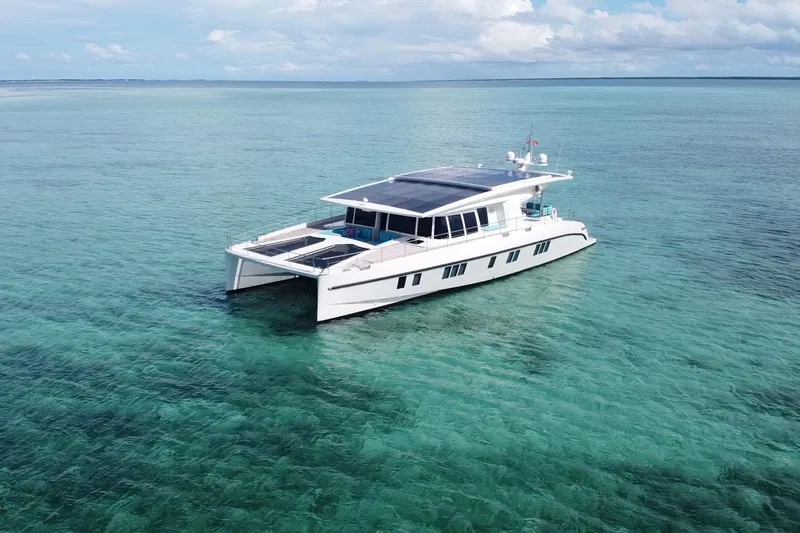 Firefly Yacht Photos Pics Luxurious 2018 Serenity 64 yacht on clear turquoise waters under a partly cloudy sky.