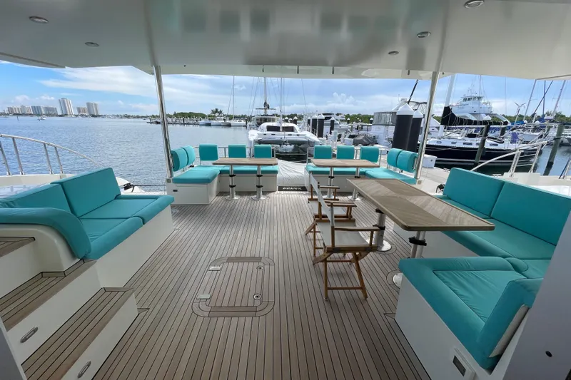 Firefly Yacht Photos Pics Spacious deck of 2018 Serenity 64 yacht with turquoise seating and marina view.