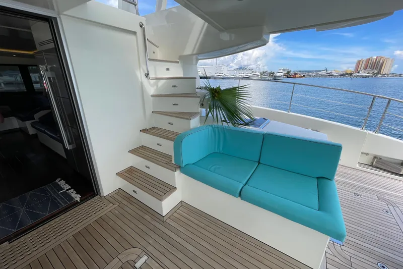 Firefly Yacht Photos Pics 2018 Serenity 64 yacht deck with turquoise seating, wooden flooring, and marina view.