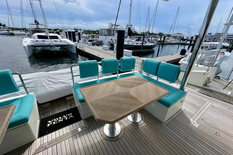 Firefly Yacht Photos Pics Luxurious Serenity 64 yacht deck with turquoise seating and wooden table, docked at marina.