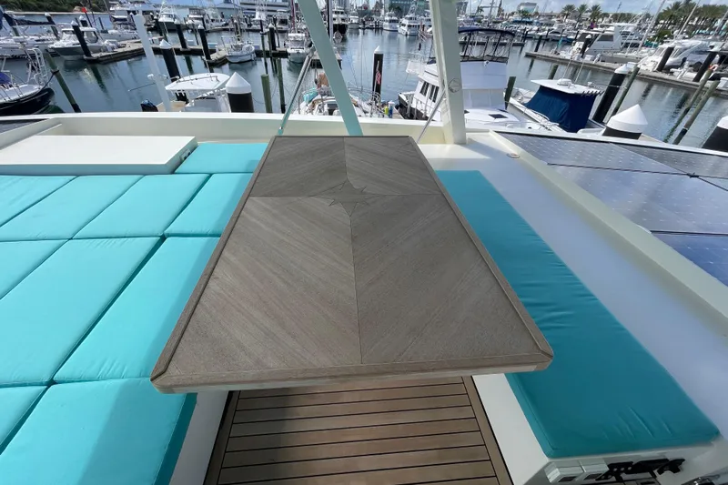 Firefly Yacht Photos Pics Luxurious Serenity 64 yacht deck with turquoise seating, wooden table, and marina view, 2018 model.