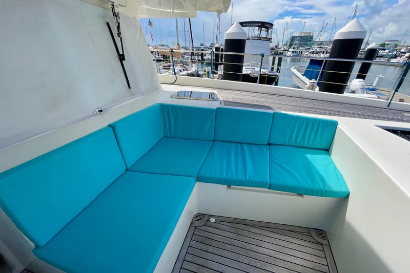 Firefly Yacht Photos Pics Luxurious Serenity 64 yacht deck with turquoise seating, docked at a marina, 2018 model.