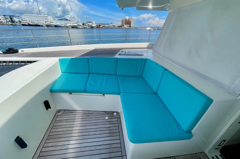 Firefly Yacht Photos Pics Luxurious Serenity 64 yacht deck with turquoise seating, overlooking marina and blue sky.