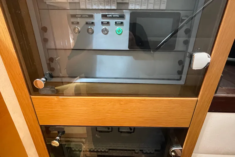 Firefly Yacht Photos Pics Control panel in a Serenity 64 yacht, 2018 model, with wooden cabinet and glass door.