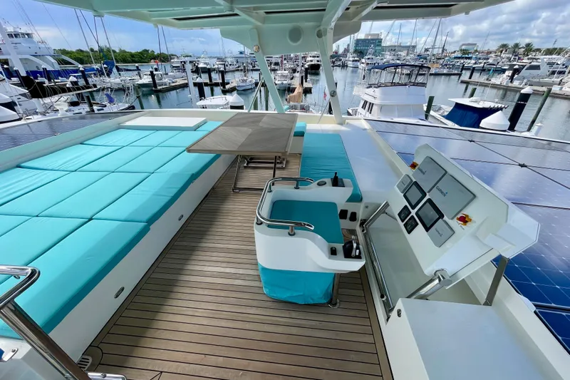 Firefly Yacht Photos Pics Luxurious Serenity 64 yacht deck with turquoise seating, solar panels, and marina view.