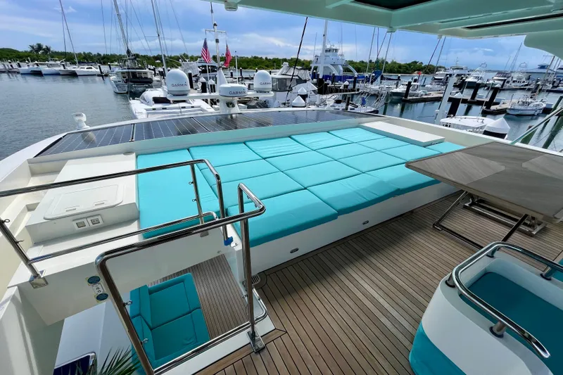 Firefly Yacht Photos Pics Luxurious Serenity 64 yacht deck with turquoise seating, solar panels, and marina view.
