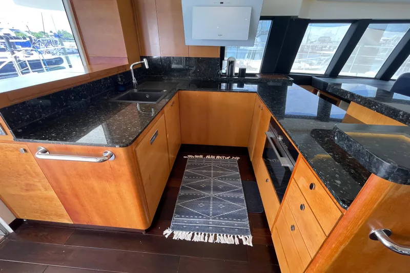 Firefly Yacht Photos Pics Luxurious 2018 Serenity 64 yacht kitchen with sleek black countertops and wooden cabinetry.