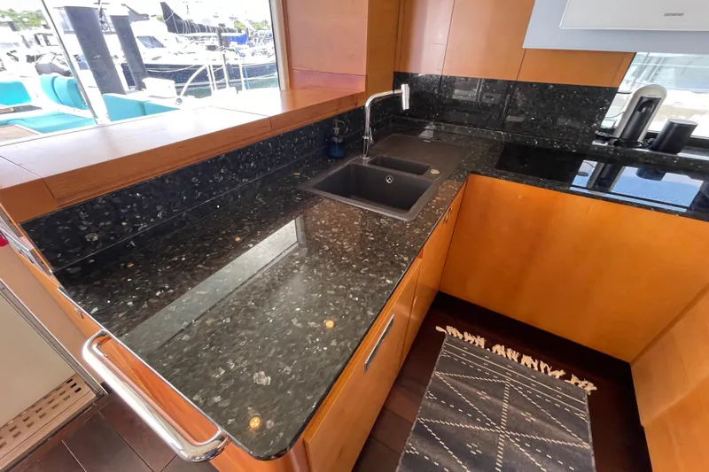 Firefly Yacht Photos Pics Luxurious yacht kitchen with sleek black granite countertops, modern sink, and wooden cabinetry, 2018 Serenity 64.