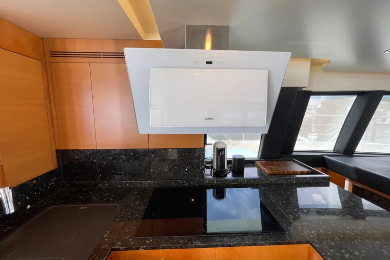 Firefly Yacht Photos Pics Modern yacht kitchen with sleek black countertops and wooden cabinetry, featuring a Siemens range hood.