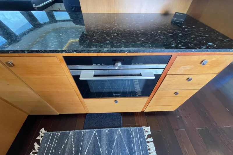 Firefly Yacht Photos Pics Modern kitchen with black granite countertop, wooden cabinets, and built-in Serenity 64 oven, 2018 model.