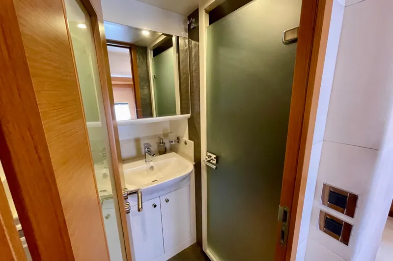 Firefly Yacht Photos Pics Compact bathroom with modern sink, mirror, and frosted glass shower door in Serenity 64 yacht.