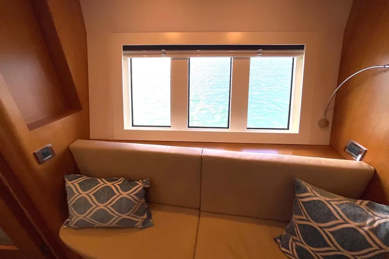 Firefly Yacht Photos Pics Cozy interior of 2018 Serenity 64 yacht with window view and decorative pillows.