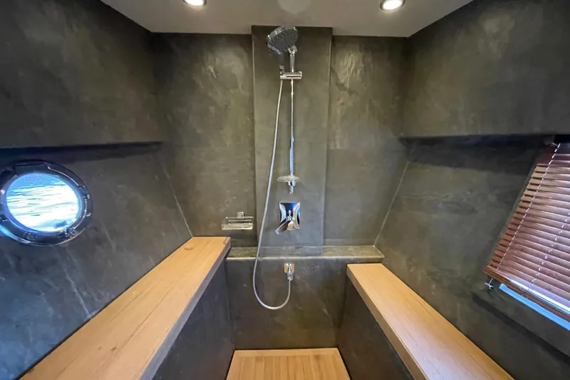 Firefly Yacht Photos Pics Luxurious yacht shower with wooden benches, porthole, and modern fixtures in Serenity 64, 2018 model.