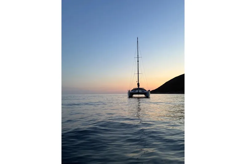 Scout Yacht Photos Pics Sailing catamaran Privilege 482 at sunset, 1992 model, on calm sea.