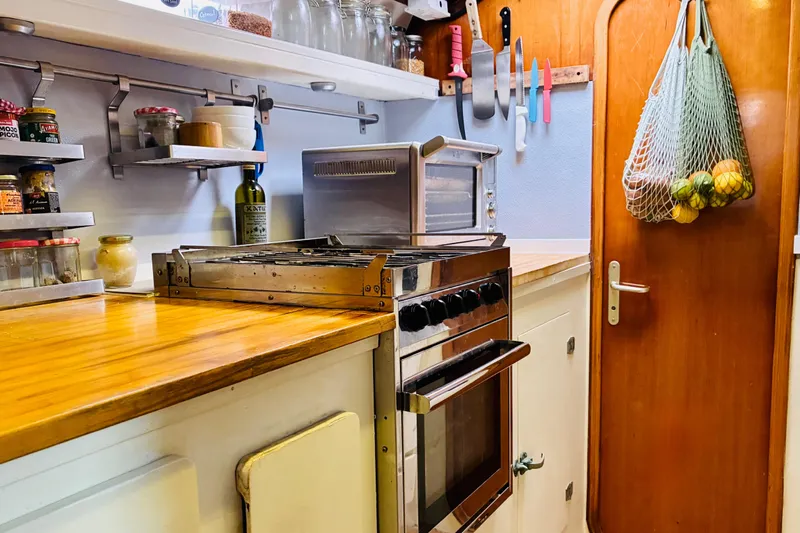 Scout Yacht Photos Pics Compact kitchen in a 1992 Privilege 482 yacht with wooden countertops and hanging fruit net.