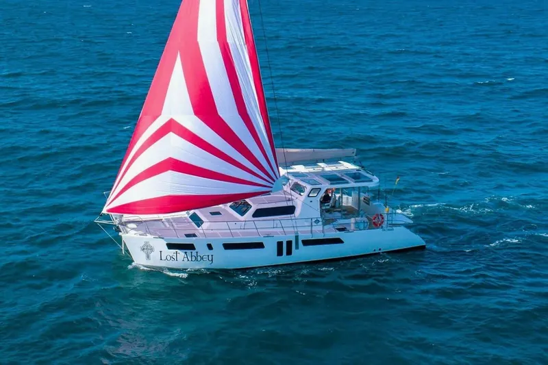 Lost Abbey Yacht Photos Pics 2021 Royal Cape Catamarans Majestic sailing with red and white sail on open sea.
