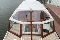 2022 STATEMENT MARINE PTS 26 boat with white canopy and wooden accents docked by water.