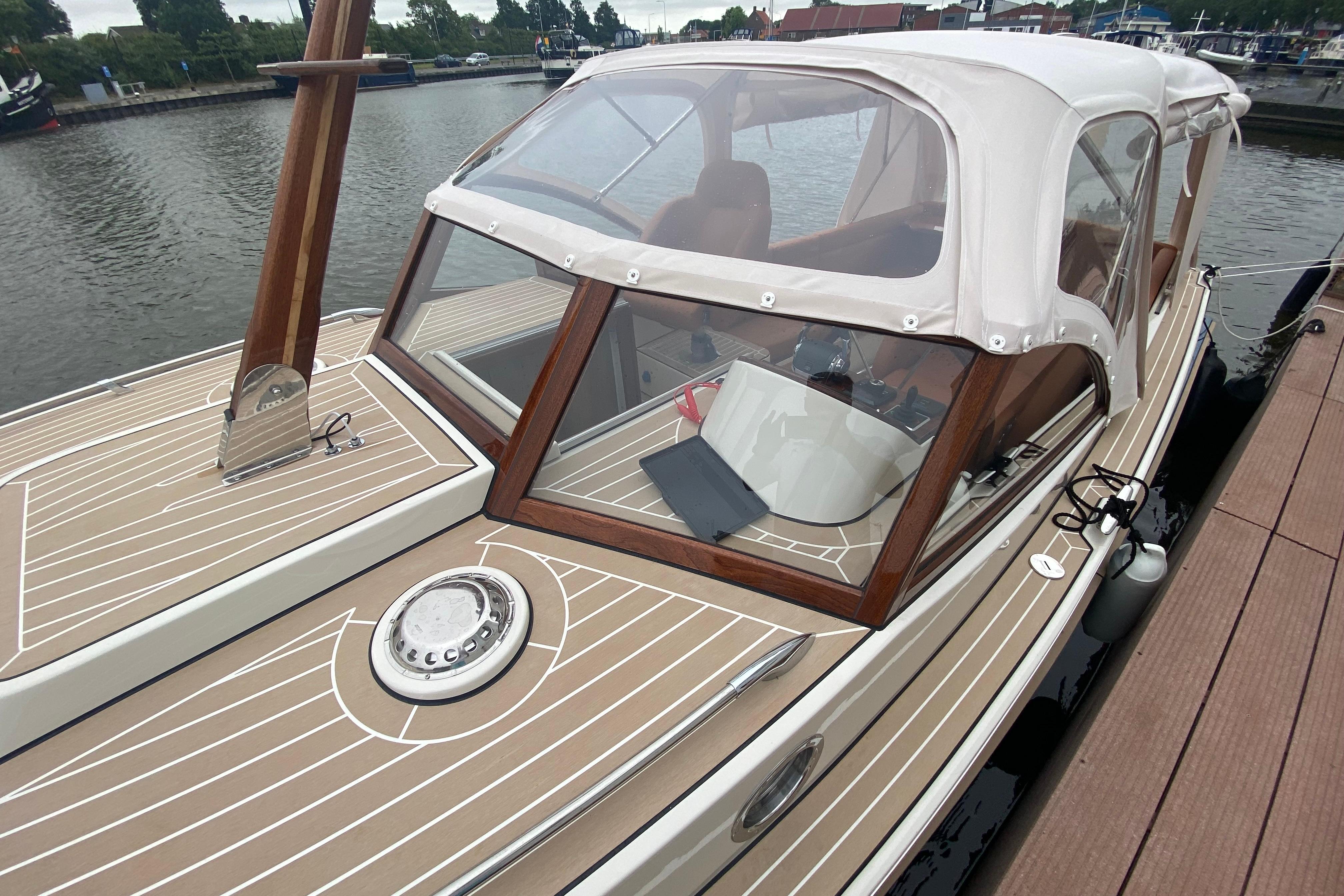 2022 STATEMENT MARINE PTS 26 boat docked, featuring elegant wood and beige detailing.