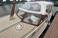 2022 STATEMENT MARINE PTS 26 boat docked, featuring elegant wood and beige detailing.