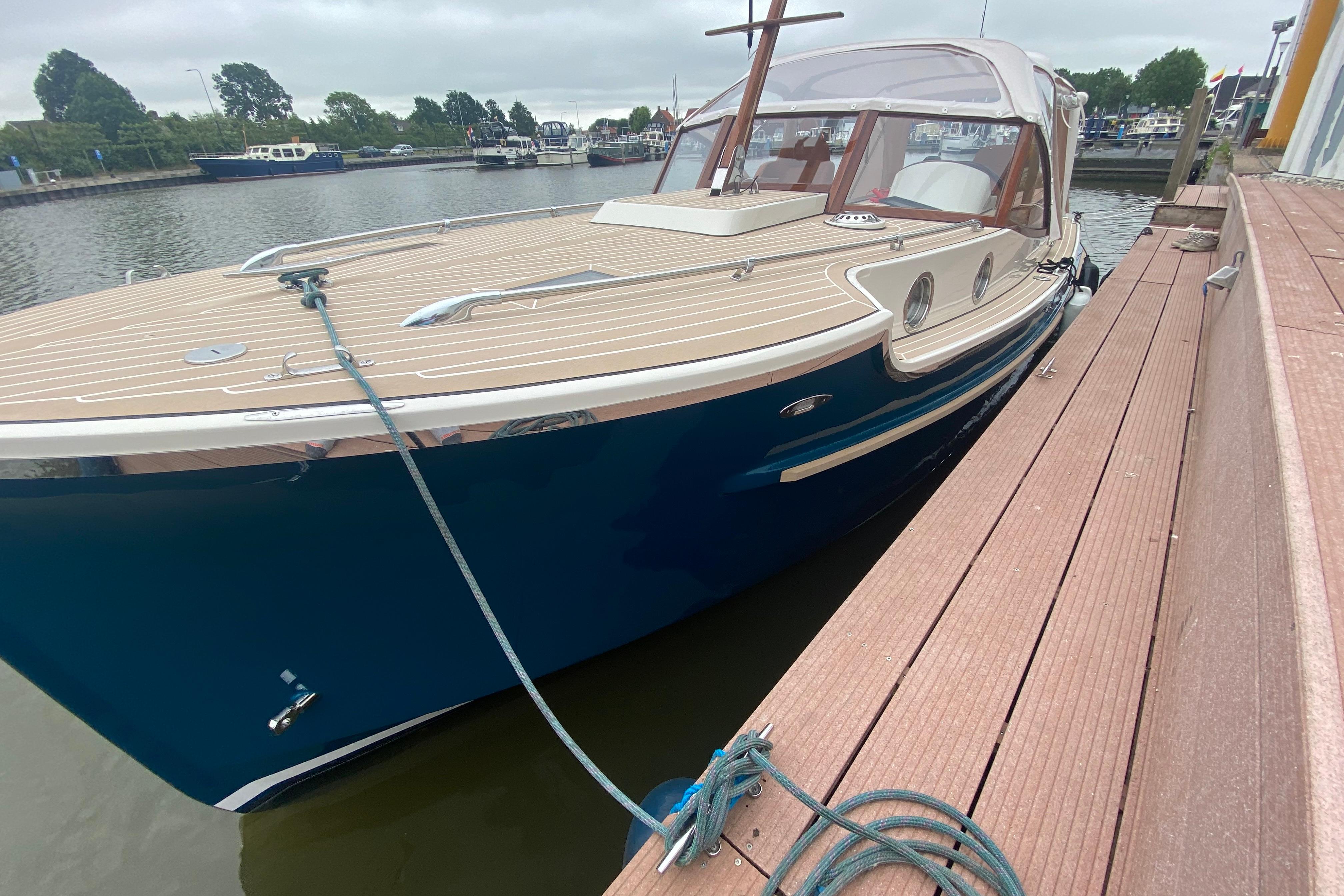 2022 STATEMENT MARINE PTS 26 boat docked, featuring sleek design and wooden deck.