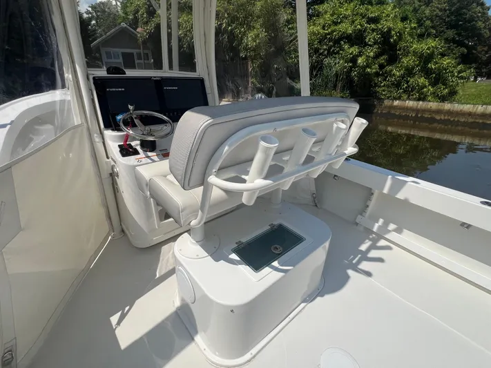  Yacht Photos Pics 2023 Parker 2801 Center Console boat interior with helm and seating, docked near lush greenery.
