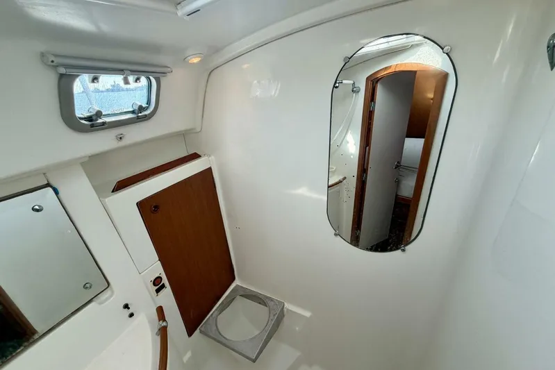 Eda Yacht Photos Pics Interior of 2000 Beneteau Oceanis 461 yacht, featuring a compact bathroom with mirror and porthole.
