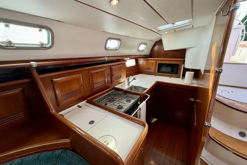 Eda Yacht Photos Pics Interior of 2000 Beneteau Oceanis 461 yacht, featuring a compact kitchen with wood cabinetry.