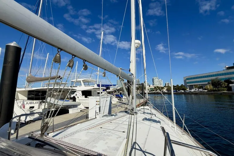 Eda Yacht Photos Pics Beneteau Oceanis 461 sailboat docked at marina, clear blue sky, cityscape background.