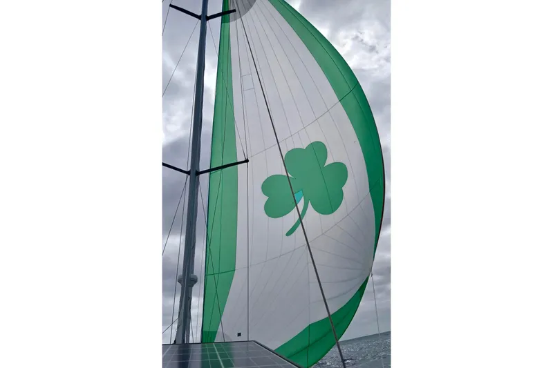 Eda Yacht Photos Pics Sail of a 2000 Beneteau Oceanis 461 with green clover design against cloudy sky.