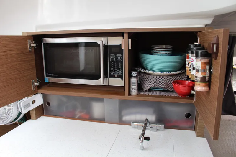  Yacht Photos Pics Kitchen area of 2021 Jeanneau Leader 9.0 WA with microwave and dish storage.