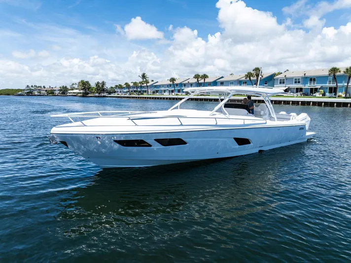  Yacht Photos Pics 2024 Intrepid 41 Valor boat cruising on a sunny day near waterfront homes.