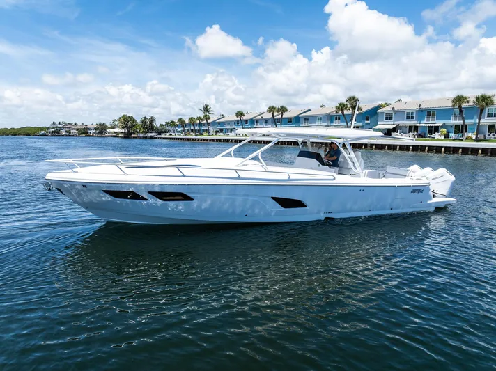  Yacht Photos Pics 2024 Intrepid 41 Valor boat cruising on a sunny day near waterfront homes.