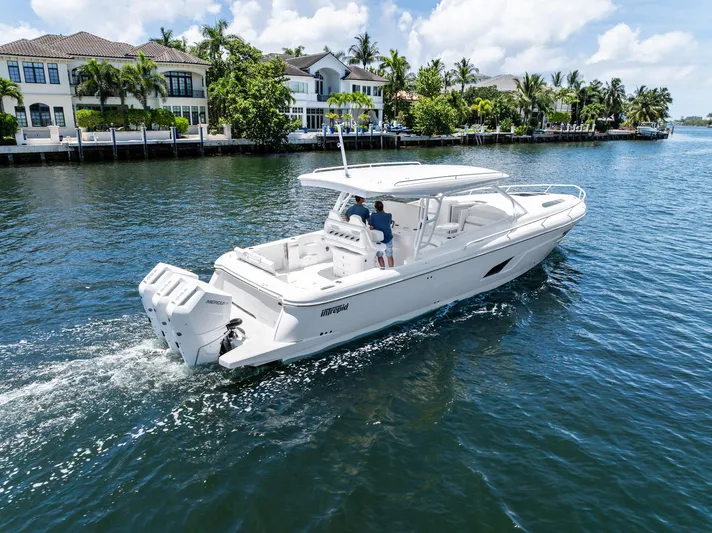  Yacht Photos Pics 2024 Intrepid 41 Valor cruising on a scenic waterfront with luxury homes.