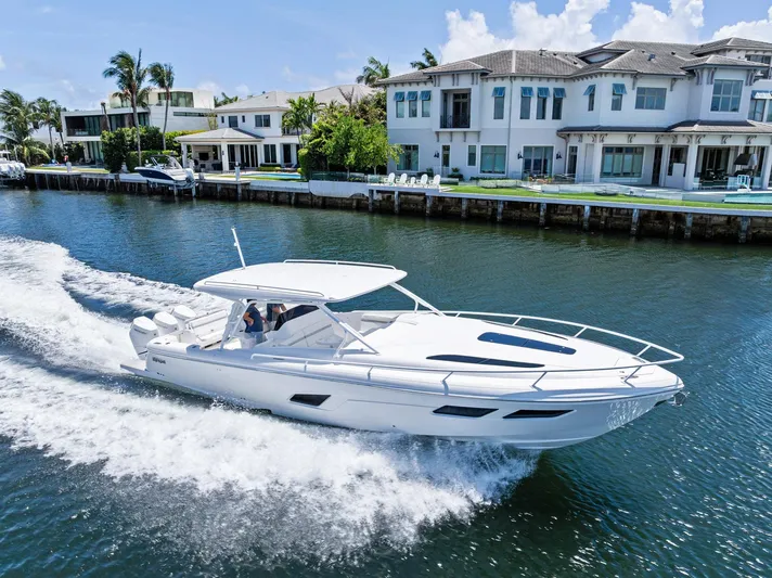  Yacht Photos Pics 2024 Intrepid 41 Valor cruising on a canal near luxury waterfront homes.