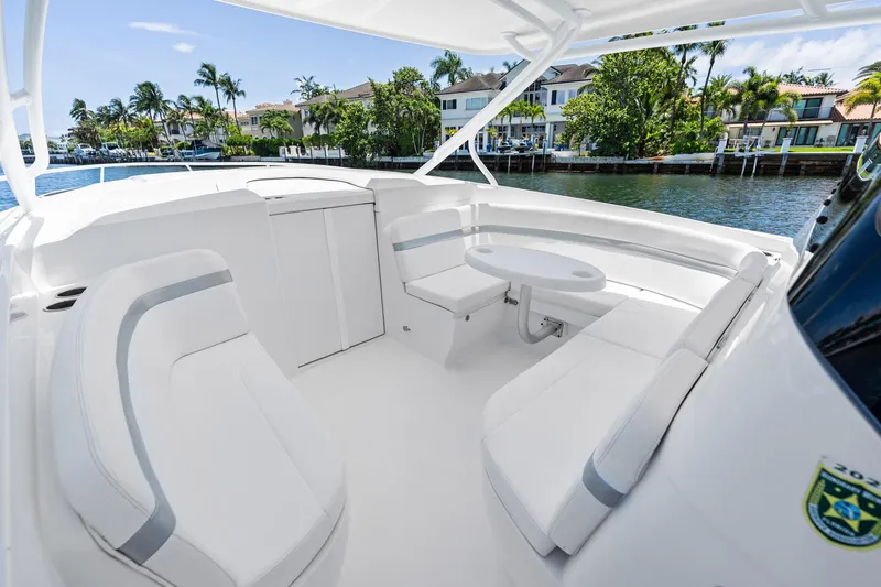  Yacht Photos Pics 2024 Intrepid 41 Valor boat interior with white seating and table, docked by waterfront homes.