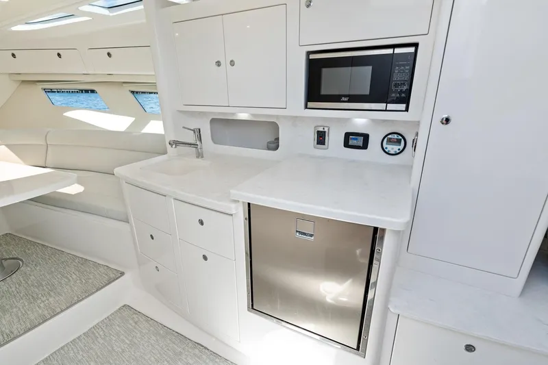  Yacht Photos Pics 2024 Intrepid 41 Valor yacht interior with modern kitchen, featuring microwave and stainless steel fridge.