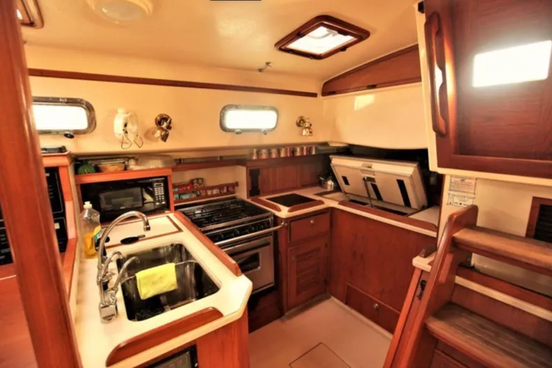 Lastochka Yacht Photos Pics Interior of 2000 Island Packet 420 yacht kitchen with wooden cabinetry and modern appliances.