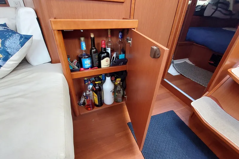 La Bella Vita Yacht Photos Pics Bar cabinet inside a 2015 Beneteau Oceanis 45 yacht, stocked with various liquor bottles.