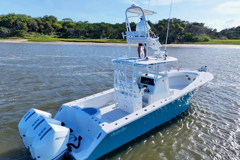  Yacht Photos Pics 2021 Onslow Bay 33 Tournament boat cruising on a sunny day near a lush shoreline.