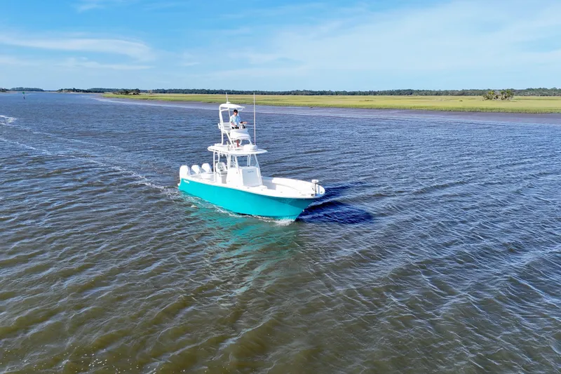  Yacht Photos Pics 2021 Onslow Bay 33 Tournament boat cruising on a calm river under a clear blue sky.