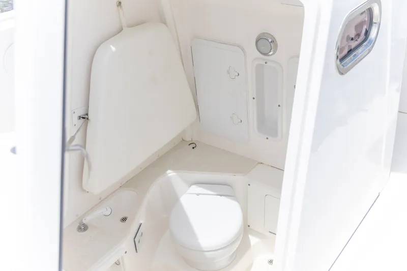  Yacht Photos Pics 2023 Edgewater 262CC boat interior with compact marine toilet and storage.