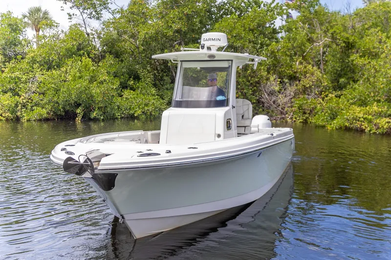  Yacht Photos Pics 2023 Edgewater 262CC boat cruising on a calm river with lush greenery.