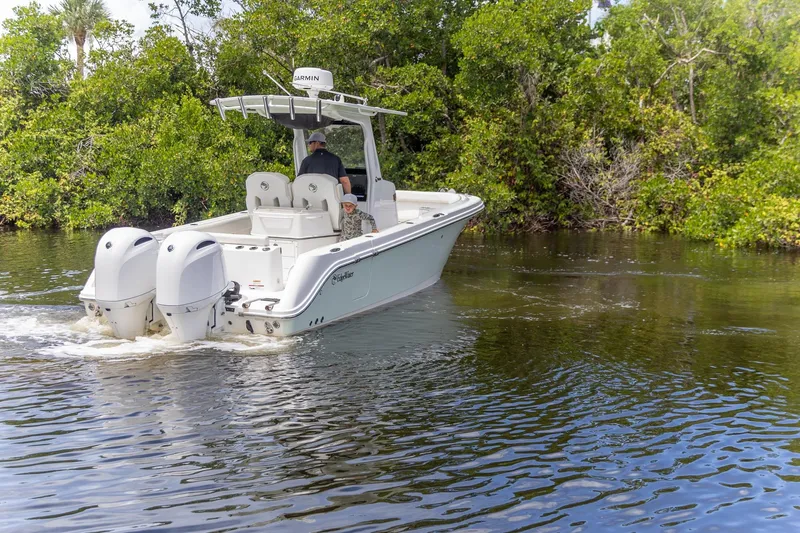  Yacht Photos Pics 2023 Edgewater 262CC boat cruising on a calm river surrounded by lush greenery.