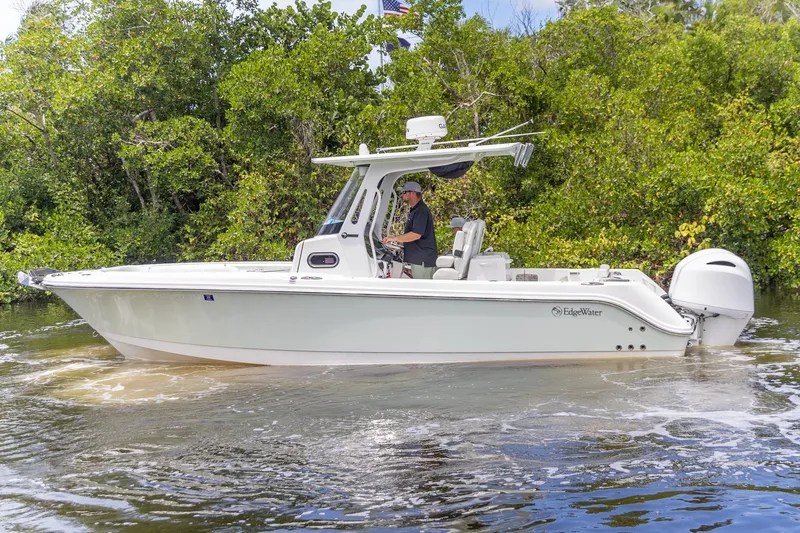  Yacht Photos Pics 2023 Edgewater 262CC boat cruising on a calm river, surrounded by lush greenery.