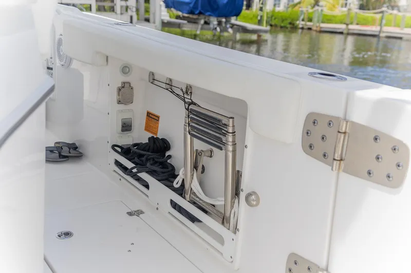  Yacht Photos Pics 2023 Edgewater 262CC boat storage compartment with ladder and ropes by the water.